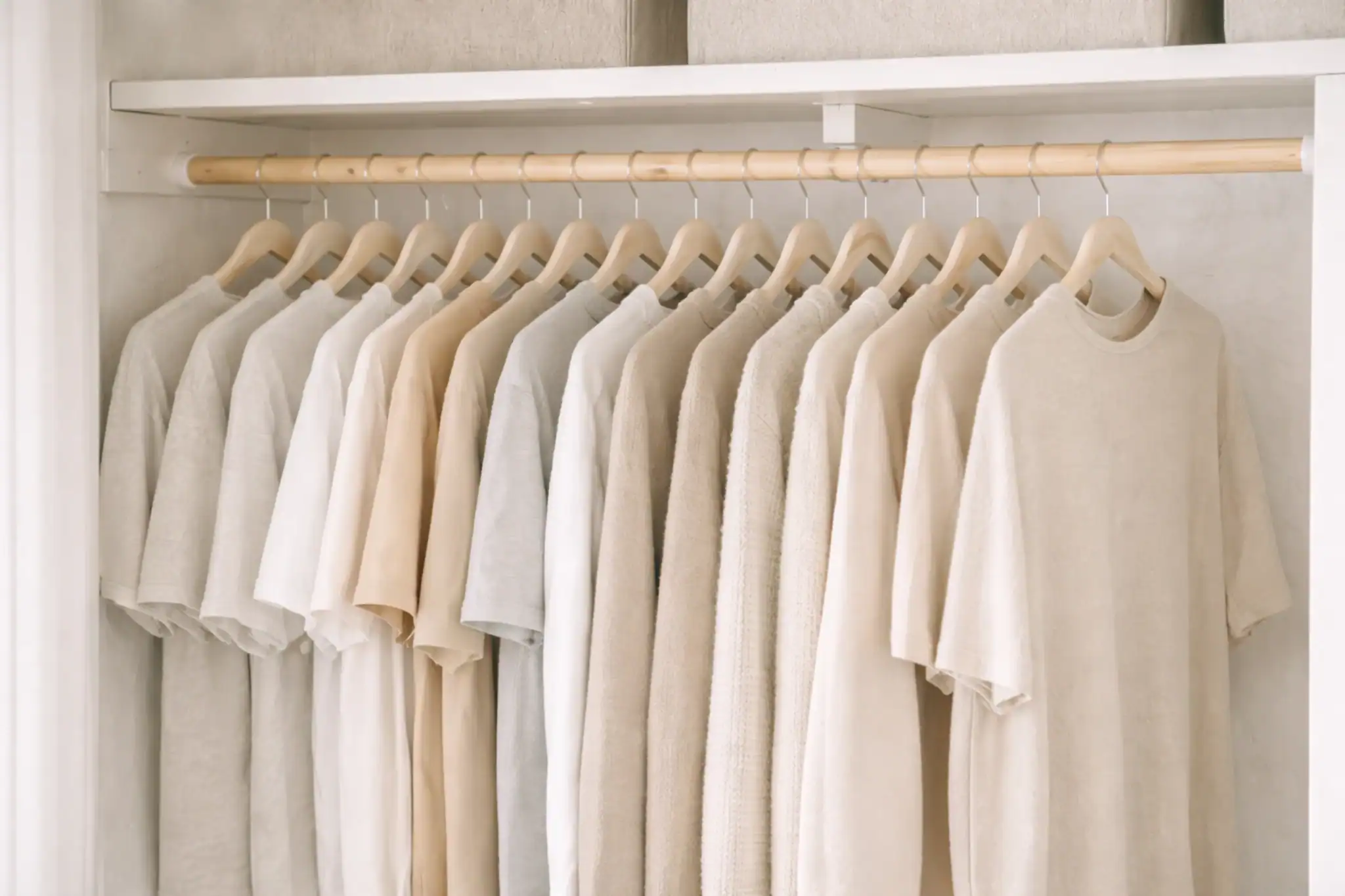 Slim matching hangers holding neutral clothing in a small closet
